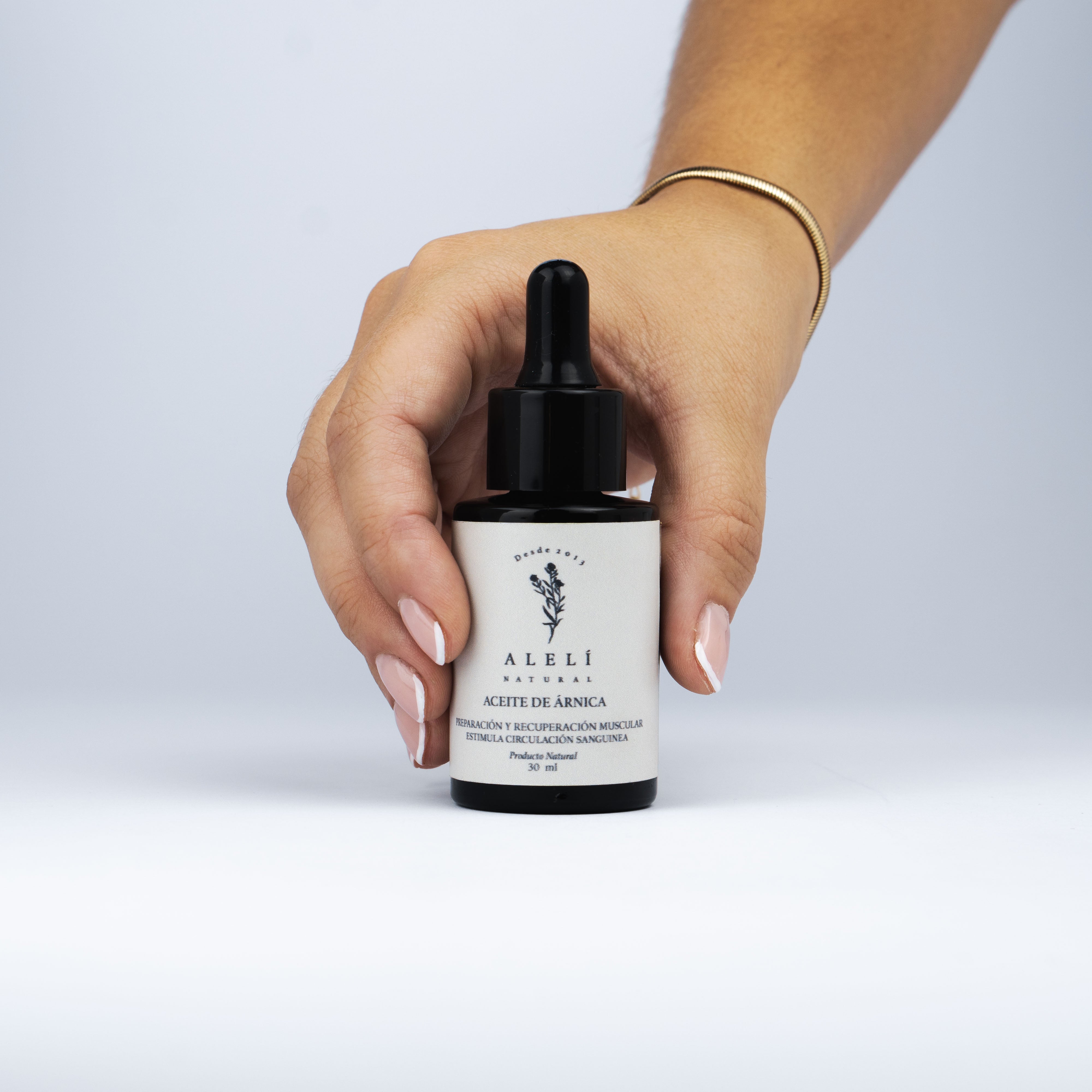 Aceite de Árnica Alelí Natural de 30 ml sostenido en una mano, mostrando tamaño y facilidad de uso.